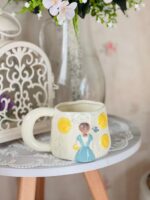 مج فتاة الحديقة بفستان لبني وزهور صفراء