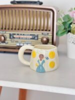 مج فتاة الحديقة بفستان لبني وزهور صفراء - Image 2