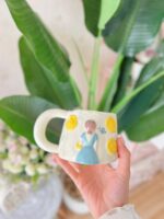 مج فتاة الحديقة بفستان لبني وزهور صفراء - Image 3